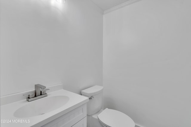 bathroom with toilet, vanity, and ornamental molding