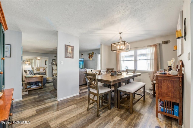 dining room featuring dark hardwood / wood-style flooring, a textured ceiling, and a chandelier