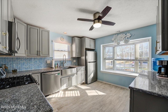 kitchen with stainless steel appliances, a wealth of natural light, gray cabinetry, and sink