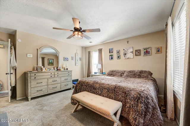 bedroom with ceiling fan, light colored carpet, and a textured ceiling