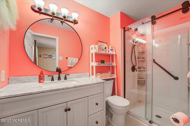 bathroom with toilet, vanity, a textured ceiling, and a shower with shower door