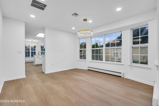 unfurnished dining area with a baseboard heating unit and light hardwood / wood-style floors