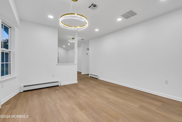 unfurnished room with ceiling fan, light wood-type flooring, and a baseboard heating unit