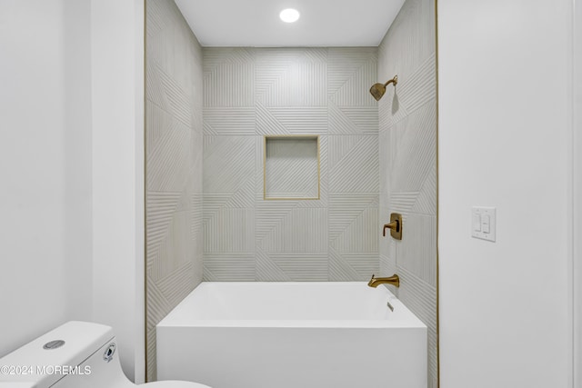 bathroom featuring tiled shower / bath combo and toilet