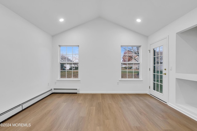 spare room featuring baseboard heating, light hardwood / wood-style flooring, and lofted ceiling