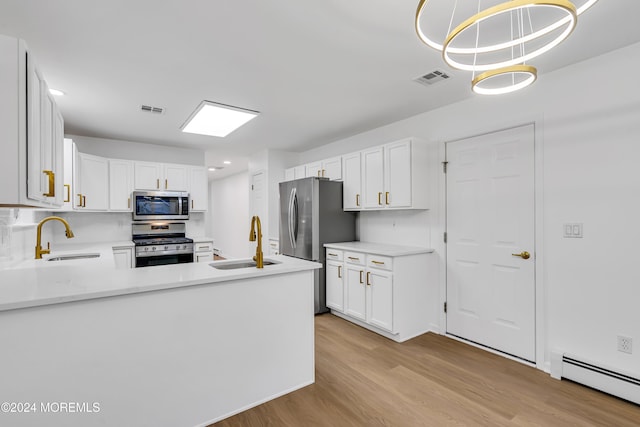 kitchen featuring hanging light fixtures, baseboard heating, white cabinets, appliances with stainless steel finishes, and sink