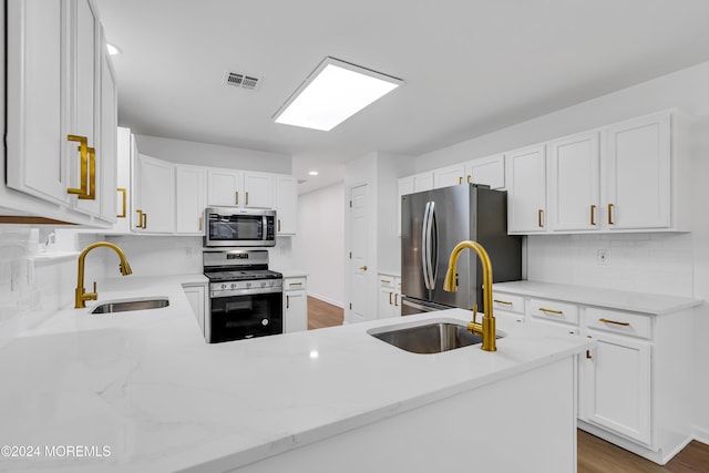 kitchen with appliances with stainless steel finishes, white cabinetry, kitchen peninsula, and sink