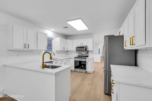 kitchen with white cabinetry, appliances with stainless steel finishes, decorative backsplash, sink, and light hardwood / wood-style flooring