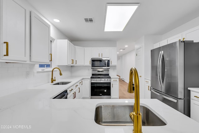 kitchen featuring appliances with stainless steel finishes, white cabinetry, and sink