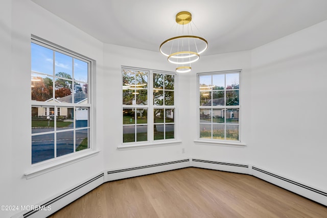 unfurnished dining area with baseboard heating, light wood-type flooring, and a chandelier