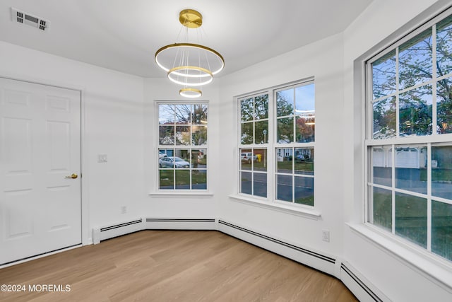 unfurnished dining area with a healthy amount of sunlight, light wood-type flooring, and a chandelier