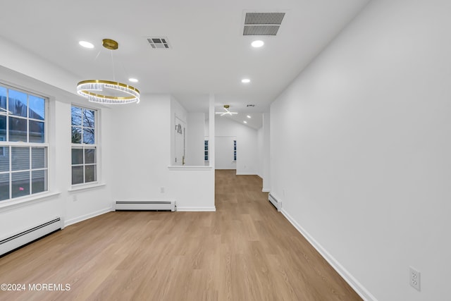 unfurnished dining area featuring ceiling fan with notable chandelier, a baseboard heating unit, and light hardwood / wood-style flooring