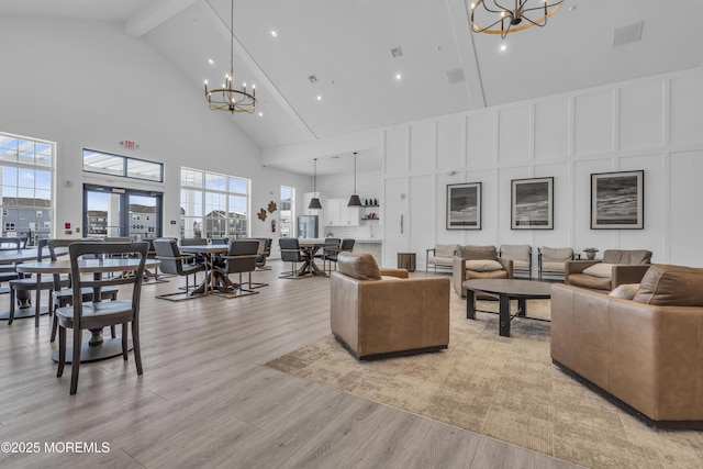 living room featuring high vaulted ceiling, light hardwood / wood-style flooring, beam ceiling, and a notable chandelier