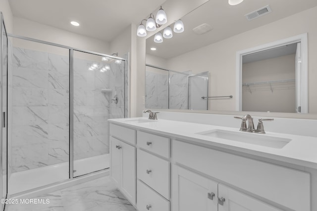 bathroom featuring a shower with door and vanity