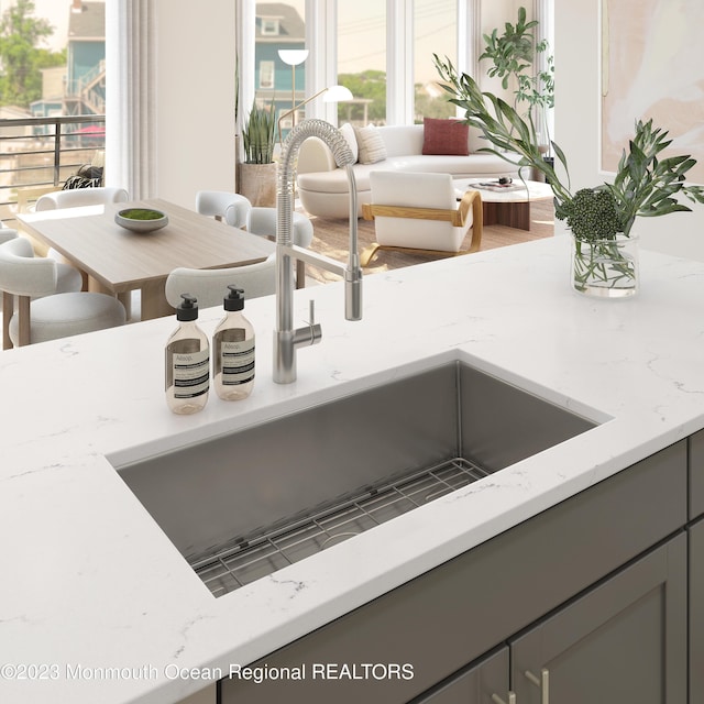 interior details with sink, light stone counters, and gray cabinets