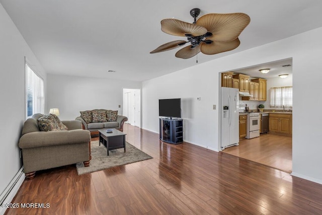 living room featuring sink, plenty of natural light, light hardwood / wood-style floors, and baseboard heating