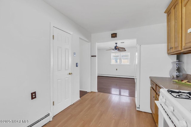 kitchen featuring a baseboard heating unit, light hardwood / wood-style floors, white gas range oven, and ceiling fan