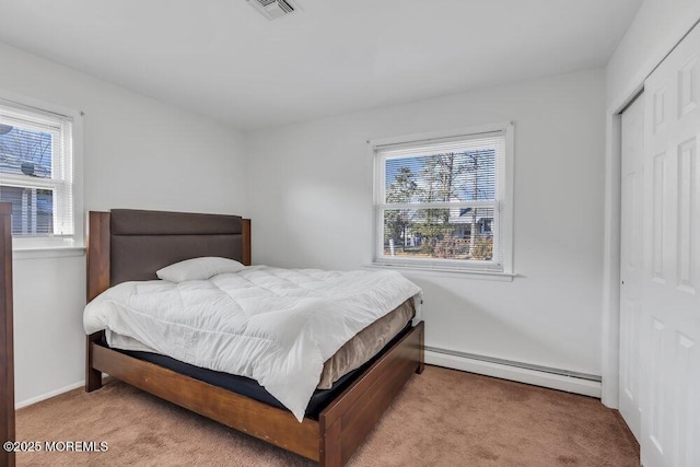 carpeted bedroom featuring a baseboard radiator and a closet