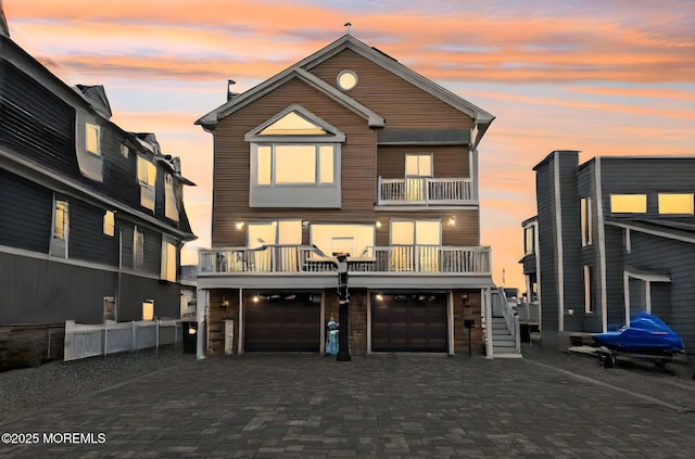 back house at dusk with a garage and a balcony