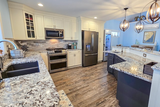 kitchen with pendant lighting, sink, light stone countertops, appliances with stainless steel finishes, and a chandelier