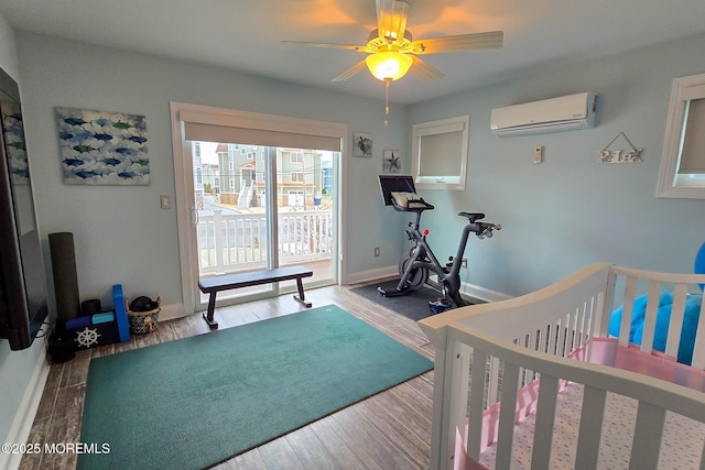 bedroom featuring ceiling fan, an AC wall unit, a crib, and wood-type flooring