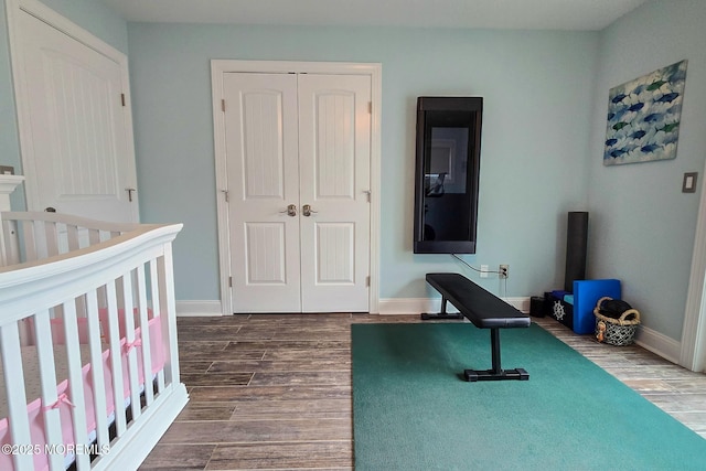 bedroom with dark wood-type flooring, a nursery area, and a closet