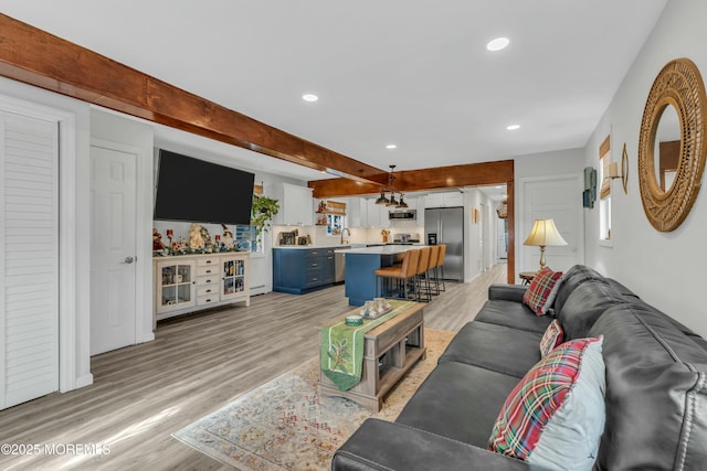 living room with light hardwood / wood-style flooring, beamed ceiling, and sink