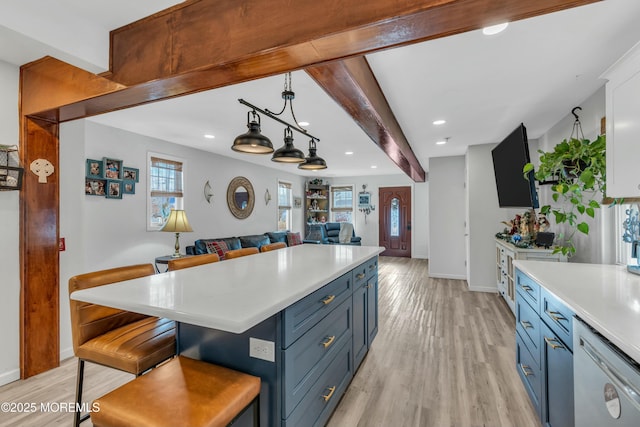 kitchen with white dishwasher, a kitchen breakfast bar, blue cabinets, and beamed ceiling