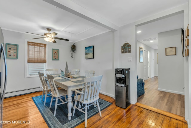 dining space with a healthy amount of sunlight, ceiling fan, light hardwood / wood-style flooring, and a baseboard heating unit