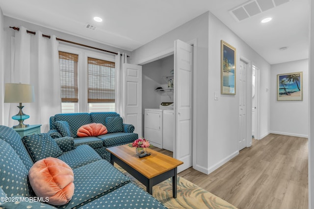 living room featuring light hardwood / wood-style floors and separate washer and dryer