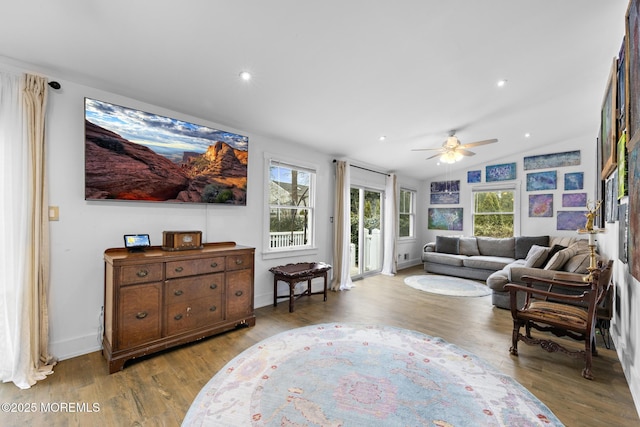 living room featuring ceiling fan, light wood-type flooring, and vaulted ceiling