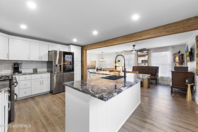 kitchen featuring stainless steel appliances, decorative backsplash, a kitchen island with sink, white cabinetry, and sink