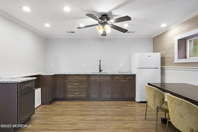 kitchen featuring sink, white fridge, light stone counters, ornamental molding, and dark hardwood / wood-style floors