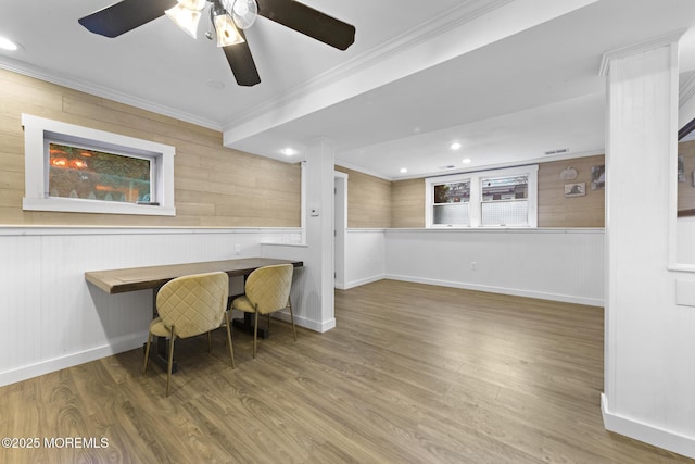 home office featuring ceiling fan, ornamental molding, wood-type flooring, and wooden walls