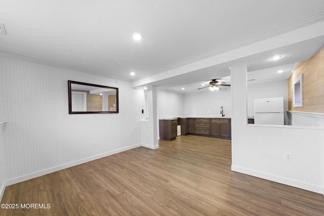 unfurnished living room featuring ornamental molding, ceiling fan, light hardwood / wood-style floors, and sink