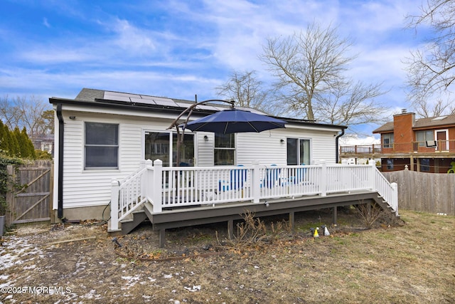 rear view of property with a wooden deck and solar panels