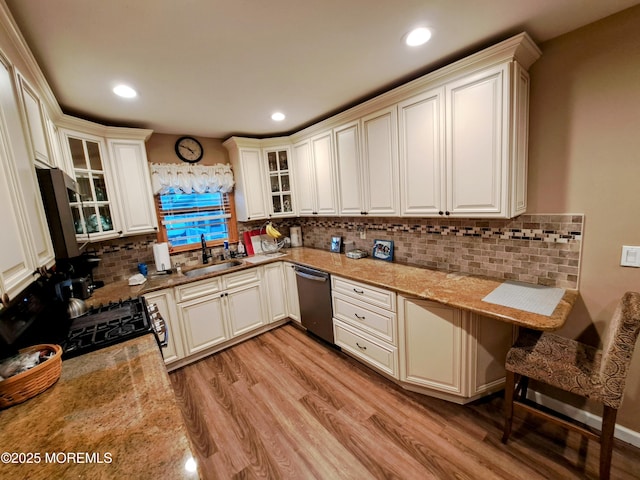 kitchen featuring light stone counters, sink, appliances with stainless steel finishes, and light hardwood / wood-style flooring