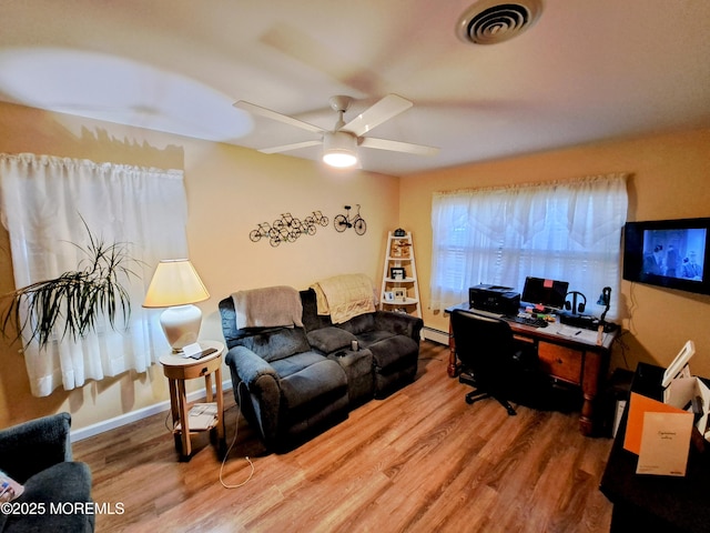 office space with a baseboard heating unit, ceiling fan, and hardwood / wood-style flooring