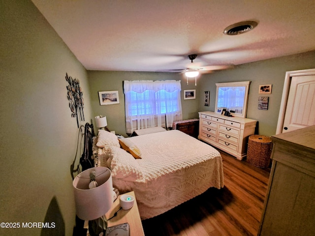 bedroom with ceiling fan, dark wood-type flooring, and a textured ceiling