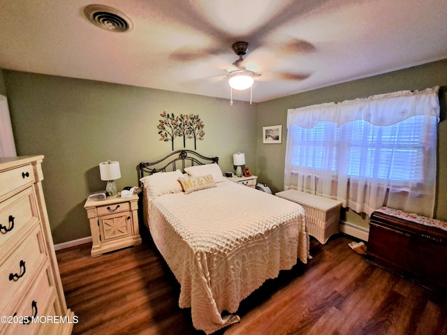 bedroom featuring a baseboard heating unit, ceiling fan, and dark hardwood / wood-style flooring