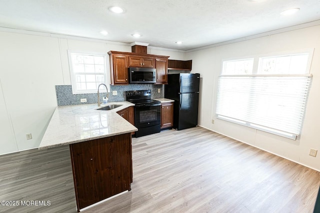 kitchen with black appliances, kitchen peninsula, sink, light hardwood / wood-style flooring, and backsplash