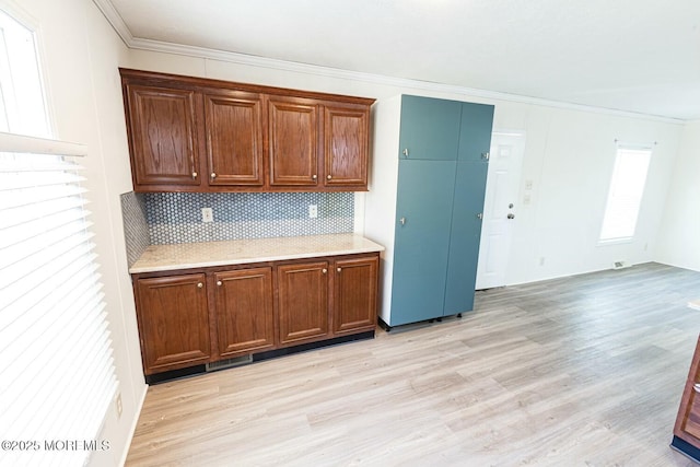 kitchen featuring ornamental molding, backsplash, and light hardwood / wood-style flooring