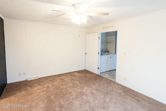 carpeted spare room featuring ceiling fan, ornamental molding, and independent washer and dryer