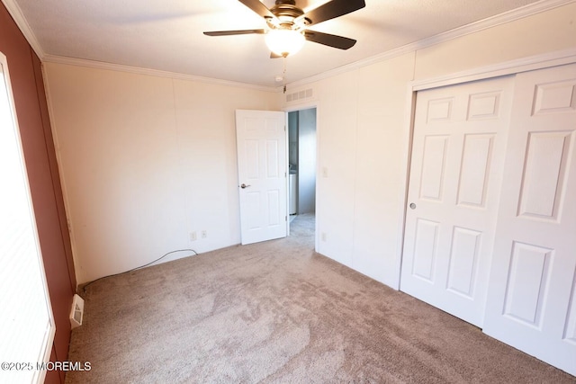 unfurnished bedroom featuring ceiling fan, light colored carpet, a closet, and crown molding