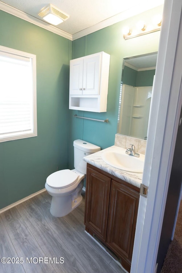 bathroom featuring toilet, walk in shower, hardwood / wood-style floors, crown molding, and vanity