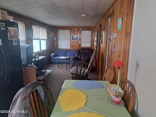 dining space with carpet floors and wood walls