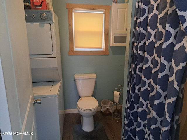 bathroom with toilet, stacked washer / dryer, and wood-type flooring