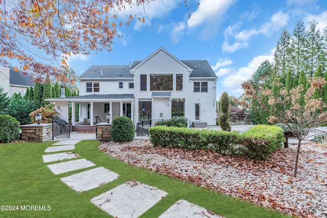 back of property with a lawn and covered porch