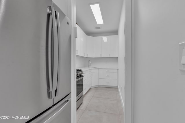 kitchen featuring sink, stainless steel appliances, white cabinetry, and light tile patterned floors