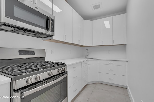 kitchen with white cabinets, stainless steel appliances, sink, and light tile patterned floors